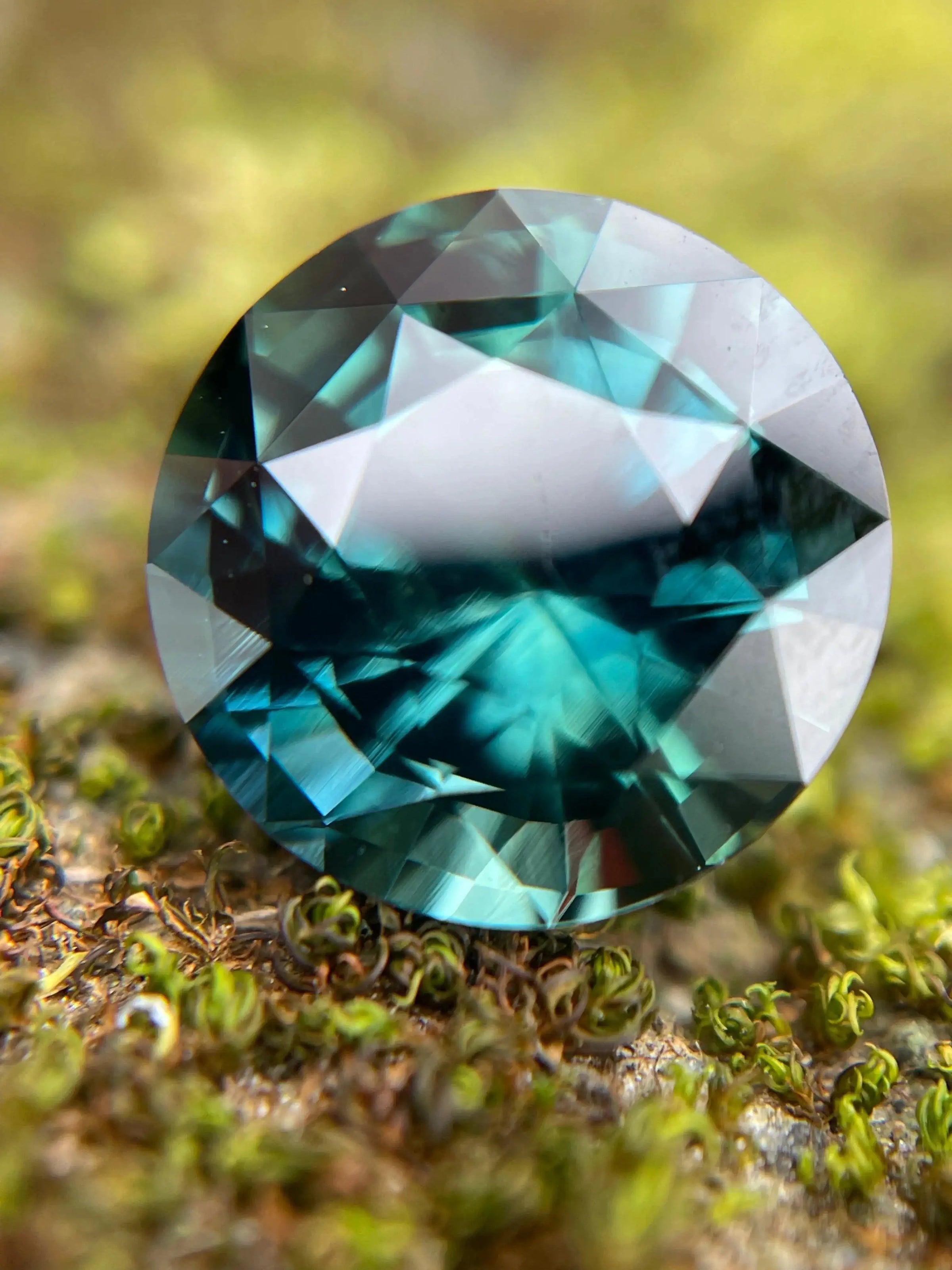 Round brilliant cut teal sapphire on a natural moss background, ethically sourced from Sri Lanka - Crystal Gem & Jewelry