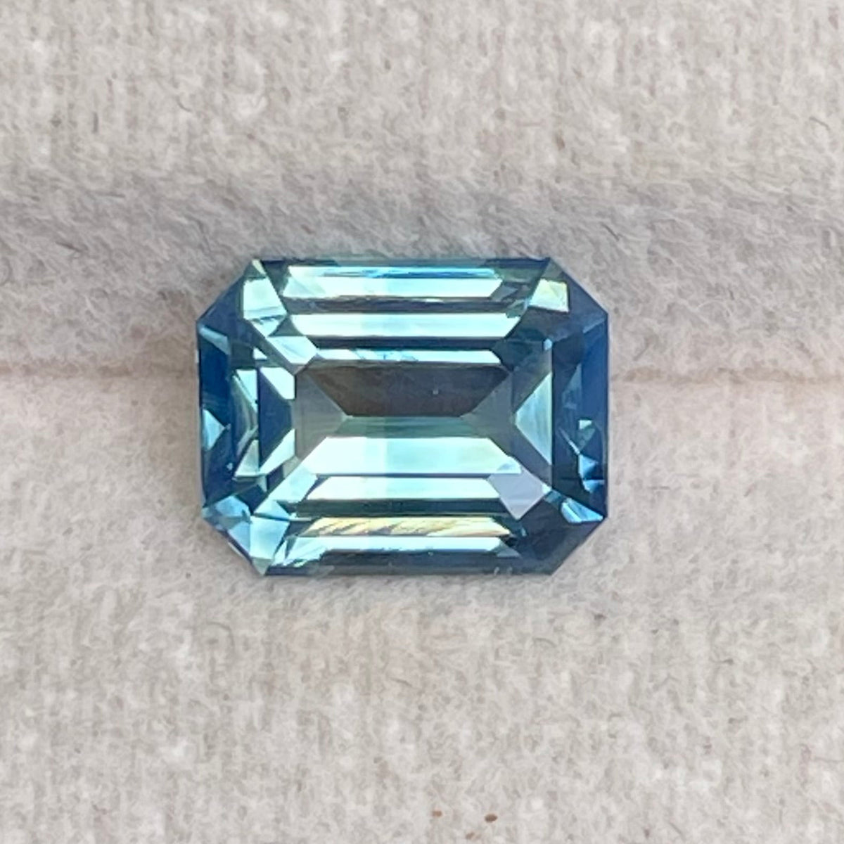 Natural 2.06 carat teal sapphire from Madagascar, emerald cut, unheated with a clean appearance, measuring 7.8 × 6 × 4.3 mm, loose earth-mined gemstone by Crystal Gem & Jewelry.